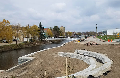 During construction of the new riverwalk, seating areas, retaining wall and pedestrian bridge over the Milwaukee River in West Bend, Wisconsin.