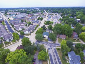 Aerial view of the community of Sun Prairie, Wisconsin, with new housing developments, commercial centers, solar arrays, and a backdrop of farming operations.