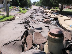 Image of flood-damaged roadway, heaving concrete and asphalt after a large flooding event in Thompson, Minnesota.